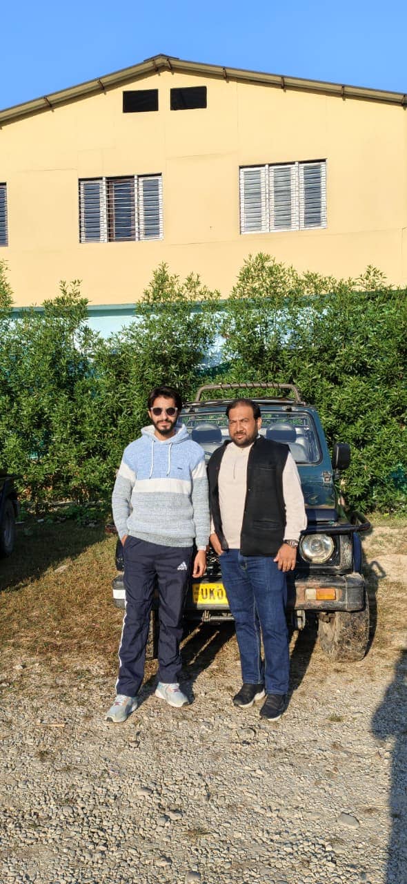 Two visitors standing beside a safari jeep